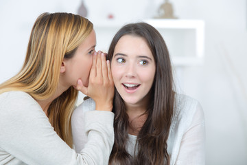 smiling woman telling secret to friend