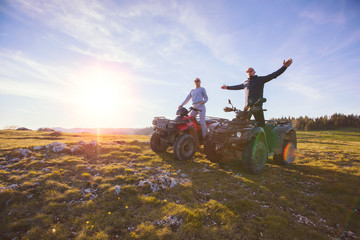 Rear view of young pair near atv. Man is showing something in distance to her girlfriend. © FS-Stock