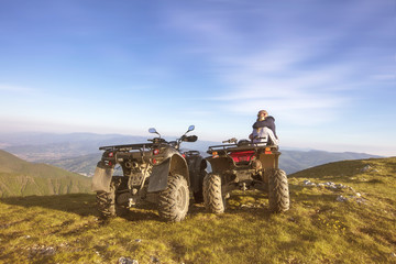 Couple driving off-road with quad bike or ATV