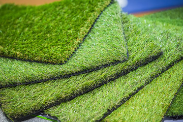 Green artificial turf rolled. Probes examples of artificial turf, floor coverings for playgrounds.