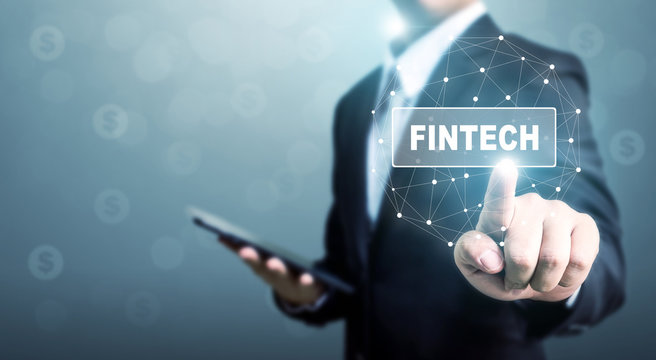 Businessman hand touching fintech (financial technology) with blurred background