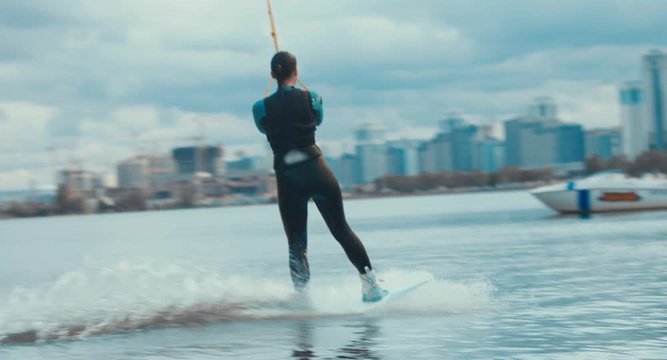 Attractive female wake boarding in a wakepark near a city. 4K UHD 60 FPS 