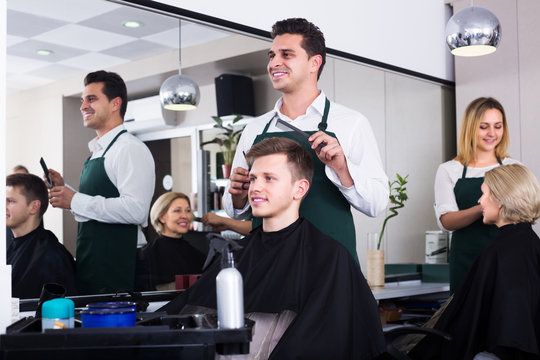 Hairdresser cutting hair of teenage