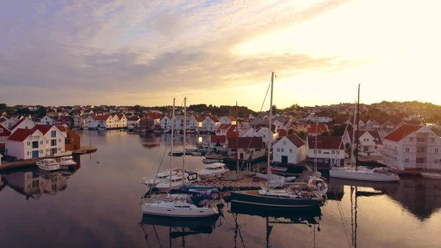 Top view of amazing port city of Skudeneshavn, Norway. Beautiful white yachts and boats stand in the sea harbor. Stunning clear sky and beautiful sunset. Typical European port city, view from above