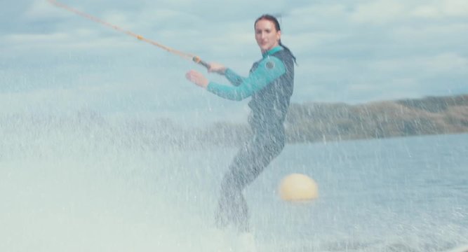 Attractive female wake boarding in a wakepark near a city. 4K UHD 60 FPS 