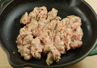 Raw sweet Italian pork sausage in cast iron frying pan skillet