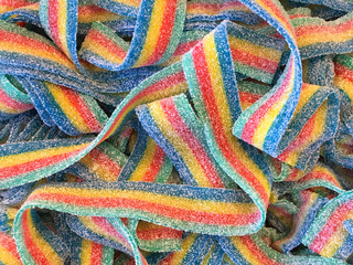 Brightly colored fruit roll candy strips covered in sugar crystals, top view close up