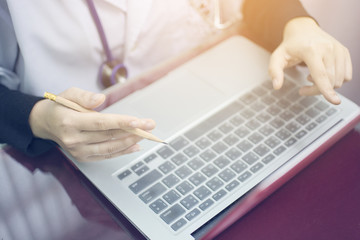 Soft focus hand holding pencil of woman doctor and finger pointing the screen of laptop to explain something for working at hospital office,  Health care and medical concept