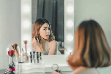 Young Beautiful Asian Woman making make-up near mirror