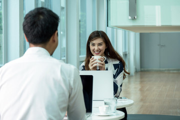 Closeup Happy Asian Beautiful young business woman holding the coffee cup and talking with businessman with formal suits in modern office, business people concept