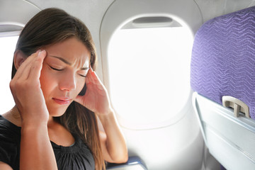 Travel plane sick woman. Fear of flying girl in airplane airsick with stress headache and motion sickness or airsickness. Person in airplane with aerophobia scared of flight frustrated sitting.