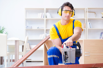 Repairman carpenter cutting sawing a wooden plank with a circula