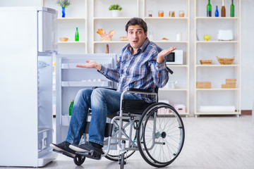 Obraz na płótnie Canvas Young disabled injured man opening the fridge door 