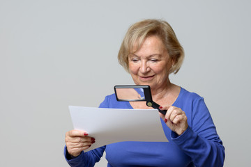 Smiling elderly woman using a magnifying glass