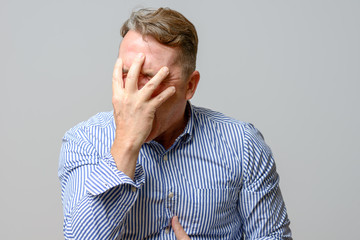 Middle aged man covering his face with his hands