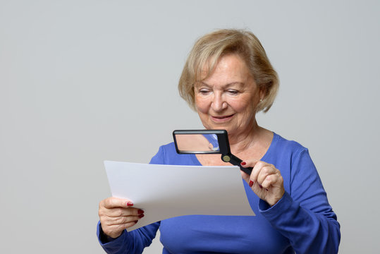 Smiling Elderly Woman Using A Magnifying Glass