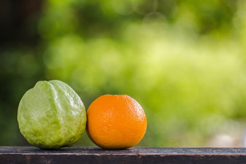 Guava fruit And Orange on wooden table On a blurred outdoor nature background