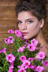 Naklejka premium Beautiful young woman holding a pot of ampel Petunia flowers