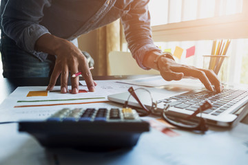 Accountants work analyzing financial reports on a laptop at his office, business concept