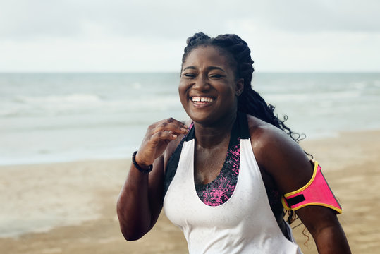 Cheerful african runner jogging during outdoor workout on beach