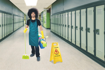 Afro maid standing with a wet floor sign