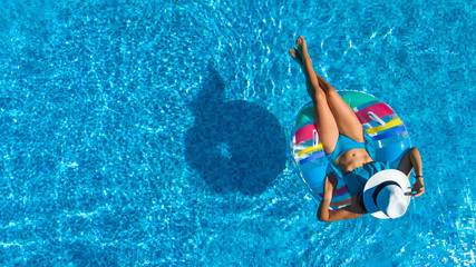 Aerial top view of beautiful girl in swimming pool from above, relax swim on inflatable ring donut...