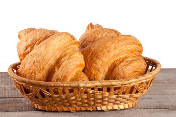 croissant in wicker basket on a wooden table with white background