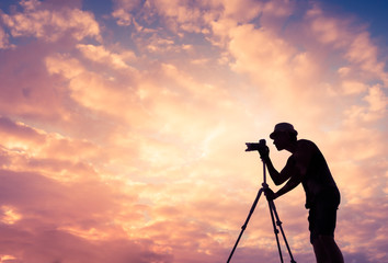 Silhouette of male photographer taking picture of colorful sunset.  