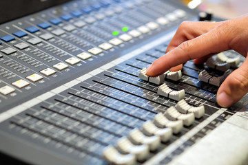 Sound engineer's fingers are pressing the button audio controller in recording room.