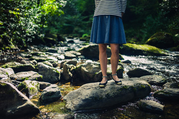 Woman in skirt standing on rocks in river