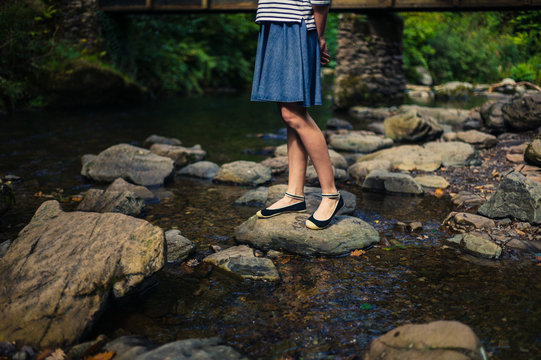 Woman in skirt standing on rocks in river
