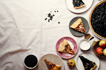 Pieces of traditional autumn pies arranged on table, covered with white linen. Chanterelle mushrooms, blueberry and sweet apple fillings. Composition with copy space