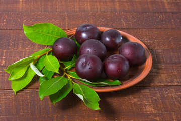 Ripe plums on a clay plate.