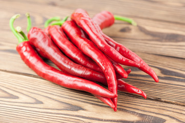 Heap of wholes red fresh ripe chili pepper on old brown wooden rustic planks