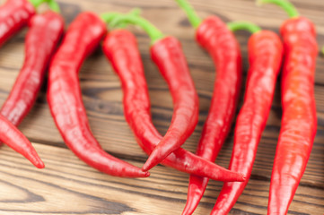 Row of wholes red fresh ripe chili pepper on old brown wooden rustic planks