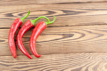 Three wholes red fresh ripe chili pepper on old brown wooden rustic planks