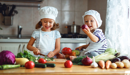 Healthy eating. Happy children prepares  vegetable salad in kitchen