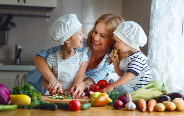 Healthy eating. Happy family mother and children  prepares   vegetable salad in kitchen.