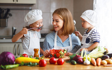 Healthy eating. Happy family mother and children  prepares   vegetable salad in kitchen.