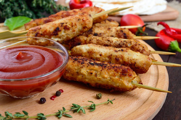 Lula kebab is a traditional Caucasian dish. Chopped meat with skewers. Serve with lavash, tomato sauce on a wooden board on a dark background.