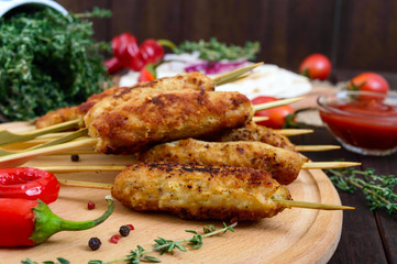 Lula kebab is a traditional Caucasian dish. Chopped meat with skewers. Serve with lavash, tomato sauce on a wooden board on a dark background.