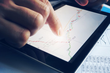 Stock broker holding tablet with candle stick graph. Trading stocks online.