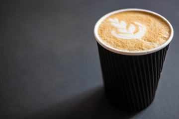 Soft focus of Latte art hot coffee in black paper cup on gray background with shadow , blurred and...