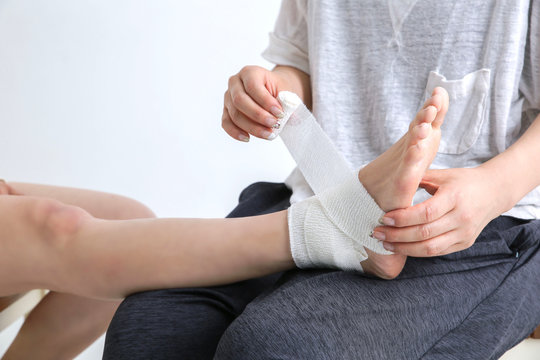 足に包帯を巻く女性
