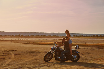 young couple on a motorcycle at sunset