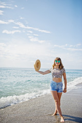Naklejka na ściany i meble Beautiful model relaxing on a beach of sea, wearing on jeans short, leopard shirt and hat.