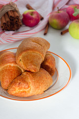 Tasty croissants with apple on white wooden background