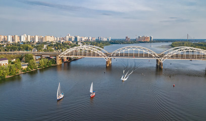 Fototapeta na wymiar Aerial top view of Darnitsky bridge, yachts and boats sailing in Dnieper river from above, Kiev (Kyiv) city skyline, Ukraine 