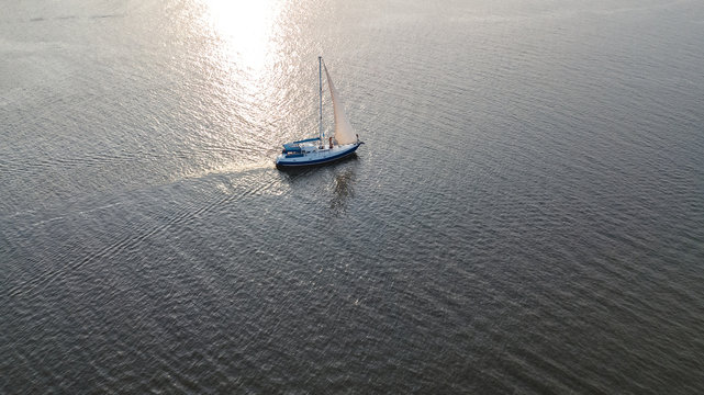 Aerial view of yacht sailing in Dnieper river on sunset from above

