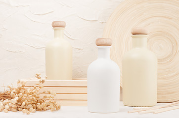 Blank beige cosmetics bottles with spikelets on white wood board, mock up. Soft elegant home decor for advertising, designers, branding identity, cover..